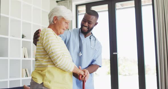 Video of happy african american male doctor supporting caucasian senior woman alt