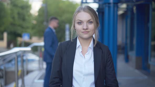 Beautiful Young Businesswoman Posing at Business Center Entrance with Blurred People  alt