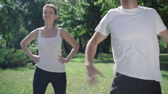 Smiling Caucasian Sportswoman Repeating Warmup Exercise After Blurred Man Bending at Front As Having alt