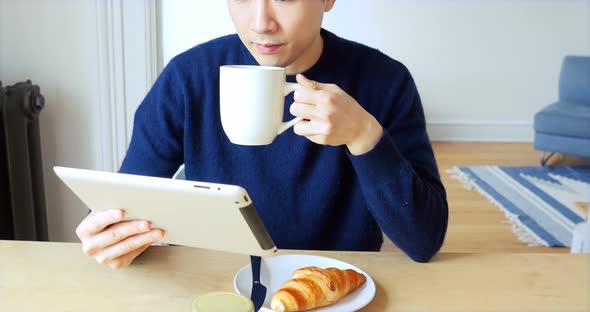 Man using digital tablet while having cup of coffee 4k alt
