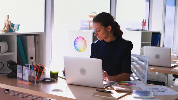 Female executive working at her desk in office alt