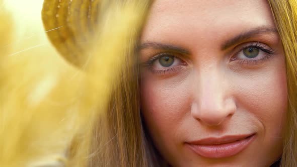 Portrait of blonde girl in boater hat smiling at camera in wheat field alt