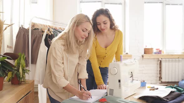 Caucasian Clothing Designer Making Notes While Preparing Tailoring in Design Room Creating New Dress