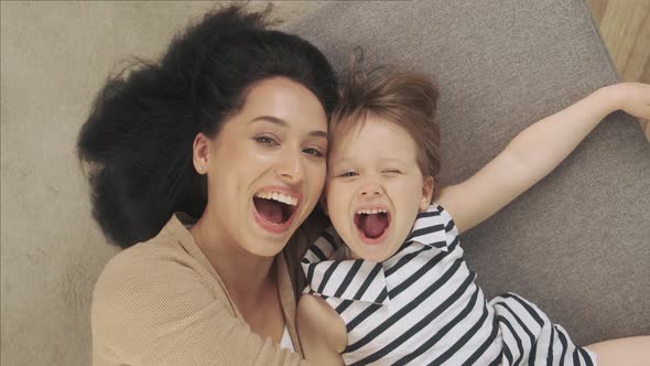Mother and Her Daughter Lie on the Couch and Take a Selfie alt