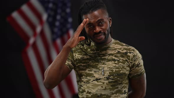 Portrait of Brave Handsome African American Recruit Saluting Posing at Black Background with USA alt