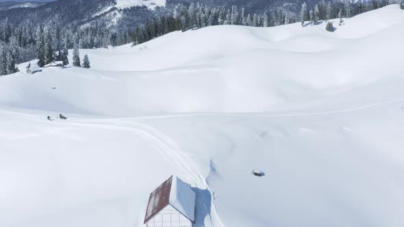 Aerial View Man on Snowmobile Riding Snowboarder on Snowy Slope in Winter Resort alt