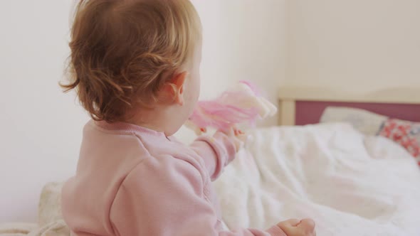 Cute baby sitting on a bed, playing, rolling and laughing alt