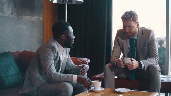 Businessmen drinking a coffee and talking in a lobby of a hotel