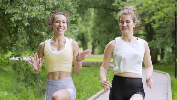 Women with Ponytails Run on Wooden Track in Park
