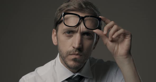 Man staring at camera and holding glasses