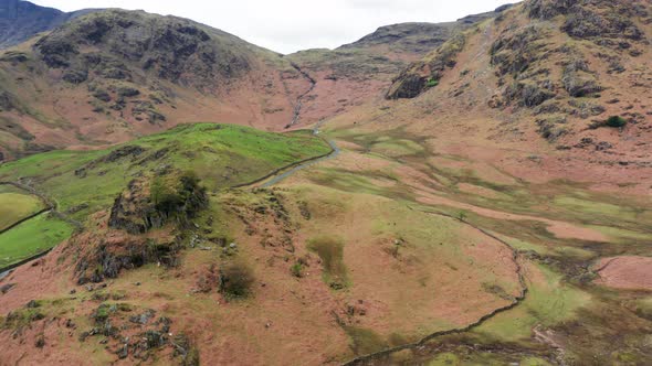 Aerial View Over Hills Towards Mountains