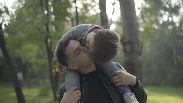Smiling Young Father Holding Son on Shoulders and Playing with Boy alt