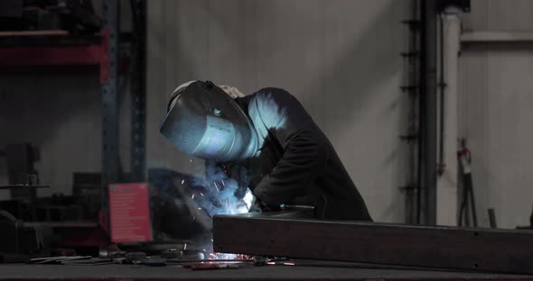 Industrial Worker In Protective Mask And Suit Welding Metal In A Factory