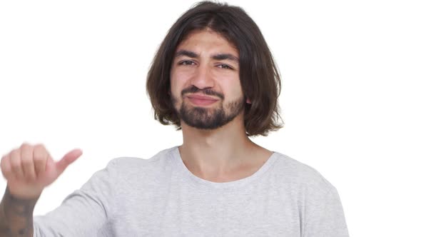 Longhaired Caucasian Guy Gesturing His Thumb Down Isolated Over White Background in Slowmotion alt