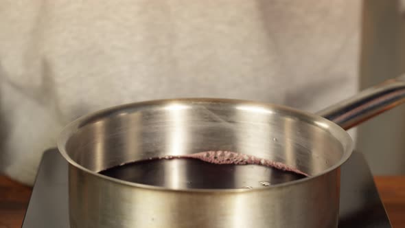 Woman Cooking Mulled Wine Gluhwein with Apples and Oranges Recipe alt