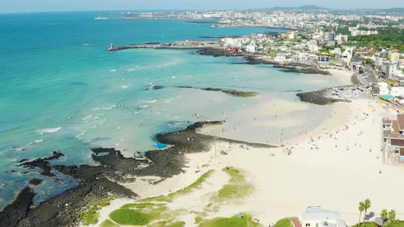 A wide sea with a view of the horizon and a beach with people enjoying a vacatio alt