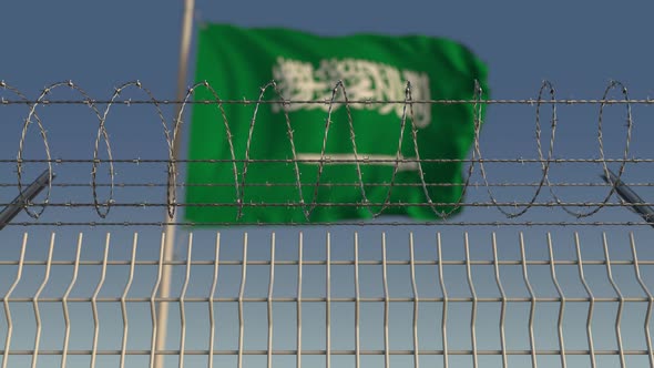 Barbed Wire Against Waving Flag of Saudi Arabia alt