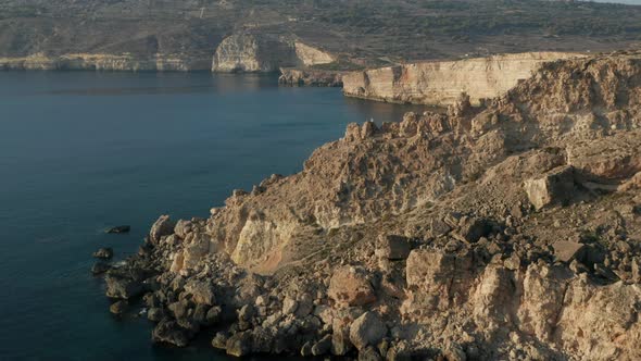 Aerial Dolly Forward Over Beige Brown Rocks in Calm Blue Ocean Revealing Turquoise Water in alt