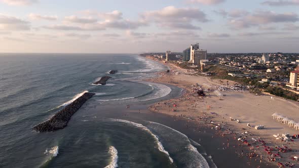 View of a beautiful tourist beach with sea and waves at sunset near the town of Herzelia in Israel alt