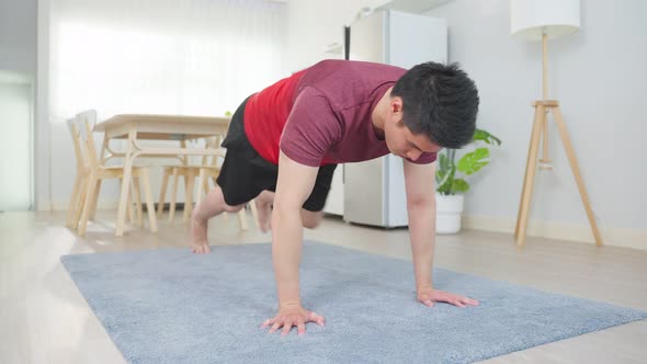 Asian handsome active young man doing exercise on floor in living room. alt