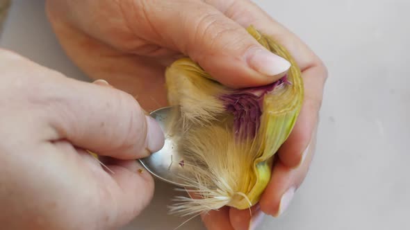 Woman Cleaning Heart of Artichokes with Spoon alt