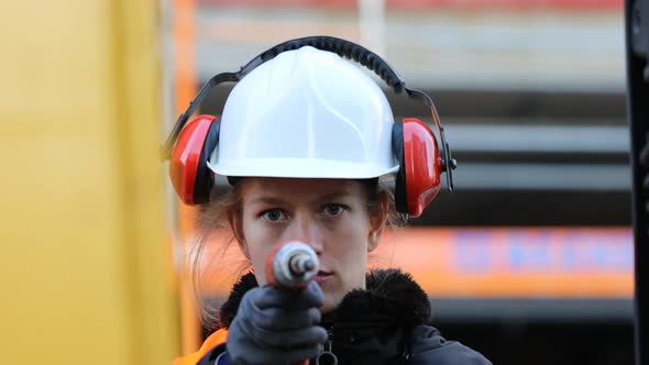 Smiling female technician holding drill and looking at camera alt