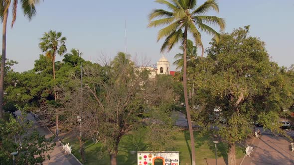 Flyover Jardín Núñez Overlooking Templo de la Merced At Background In Colima City, Mexico. Aerial Dr alt