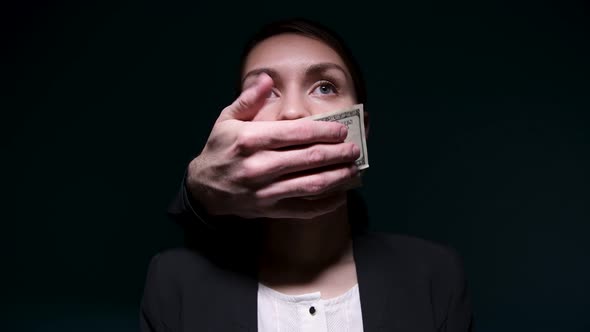 Money buys silence. Someone is covering a woman's mouth with dollars alt