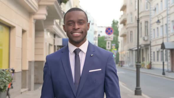 Smiling African Businessman Walking on Street alt