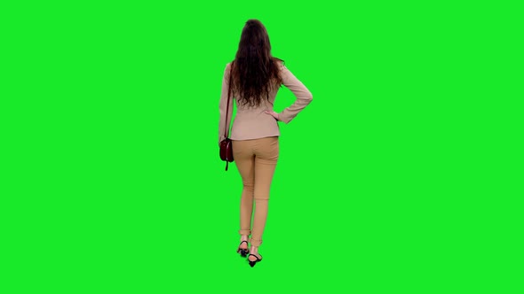 Back view of Young Stylish Woman with Shoulder Bag Walking and Stumbling on Green Screen