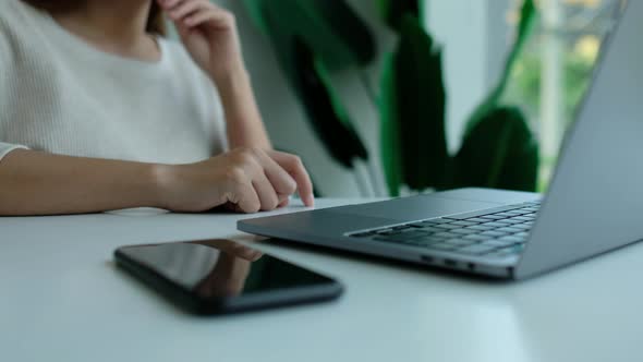 woman tapping fingers while working on laptop computer with mobile phone