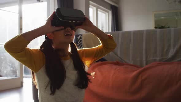 Happy asian girl at home, sitting on floor in living room using vr headset alt
