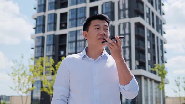 Millennial Chinese Businessman Guy Activating Virtual Assistant on Mobile Phone alt