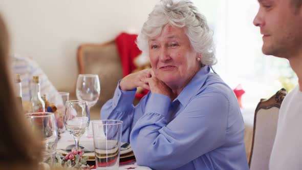 Caucasian senior woman talking while sitting on dining table alt