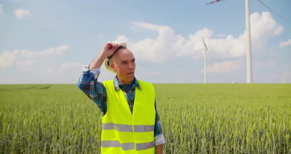 Engineer with Blueprint Analyzing Farm Against Sky alt