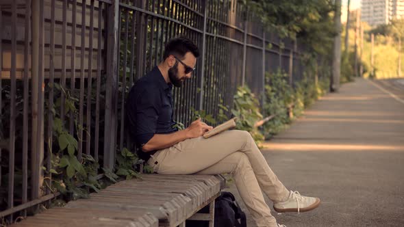 Man Reading Book On Train Station. Tourist Reading Book When Waiting Train On Electric Train Station alt