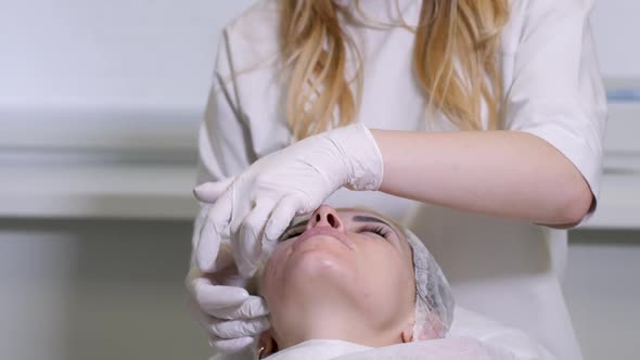 Doctor Beautician in White Rubber Gloves Doing Facial Massage alt