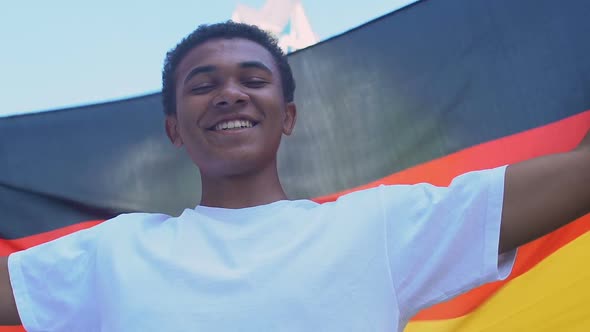 Afro-American teenager boy waving German flag outdoors alt