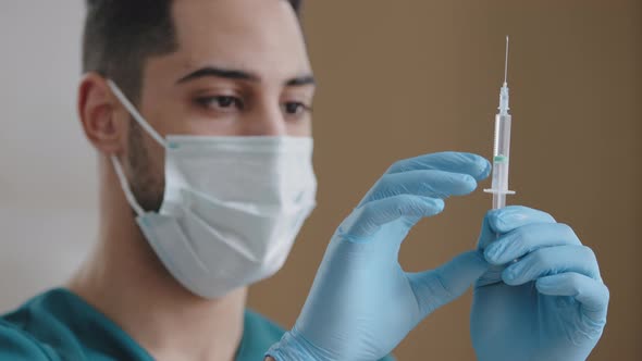 Hispanic Man Doctor Medical Surgeon Wear Medical Face Mask Gloves Pressing Filled Syringe Tapping alt