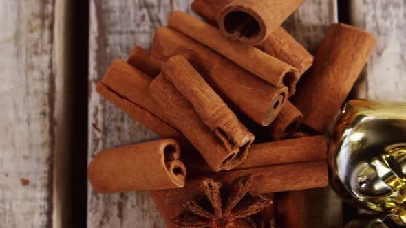 Star anise, cinnamon and jingle bells on a plank alt