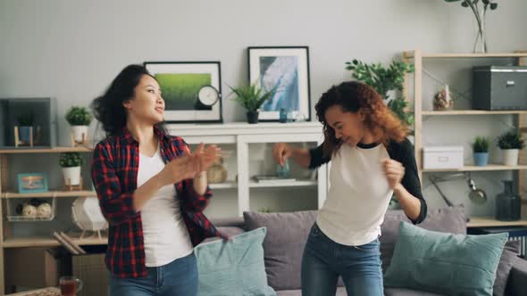 Pretty Young Women Asian and African American Are Dancing at Home Listening To Music and Having Fun alt