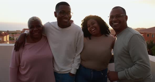 Happy african family looking and smiling in camera on patio outdoor at sunset alt