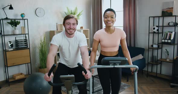 Couple which Exercising Together on Running Track and Bike Trainer and Showing Thumbs up alt