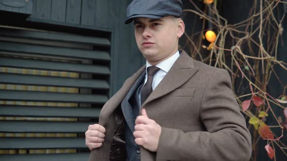 Portrait of a Stylish Businessman in Brown Coat and Hat on Wooden Background on Street alt