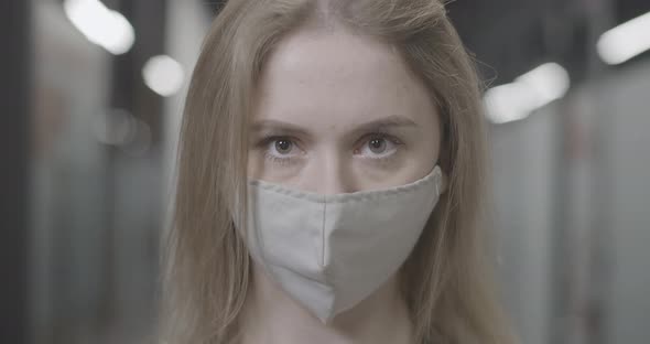Headshot of Young Confident Caucasian Woman in Covid19 Face Mask Looking at Camera Standing in alt