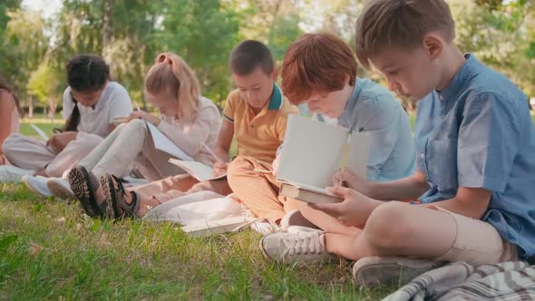 Children Drawing in Notebooks in Park during Outdoor Lesson alt
