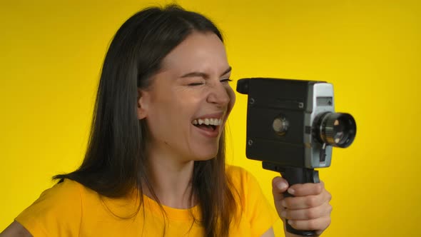A Cheerful Darkhaired Woman is Using a Retro Camcorder for Shooting Video alt