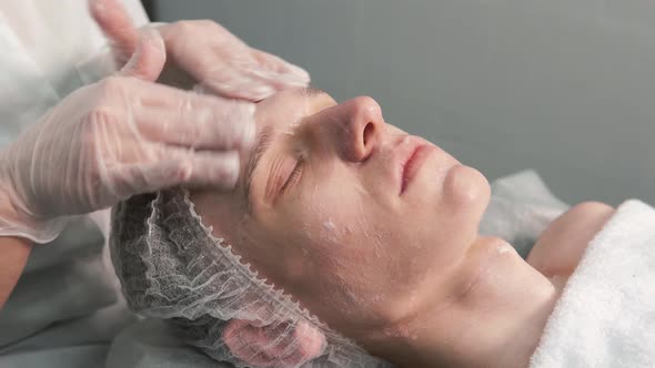 A Cosmetologist Gives a Facial Massage to a Young Man