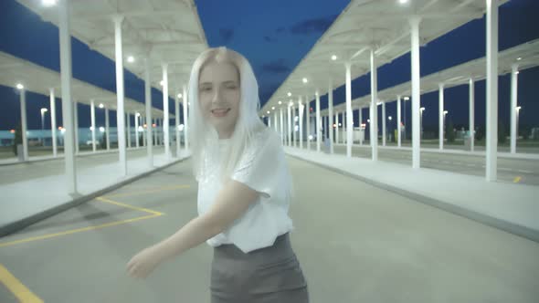 Young Beautiful Woman with White Hair in a Short Skirt is Dancing on the Background of an Empty Car alt