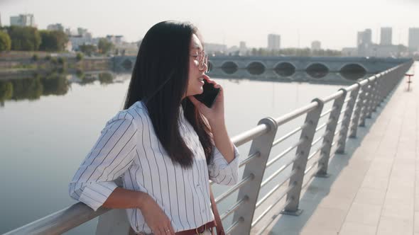 Young Asian Woman Making Phone Call Outdoors alt